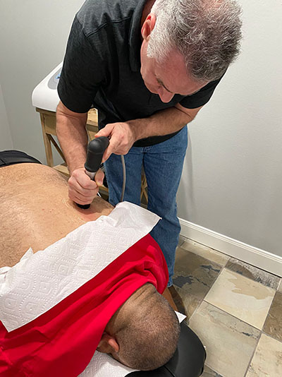 Chiropractor Conroe TX Ryan Roeder Performing Shockwave Therapy With A Patient